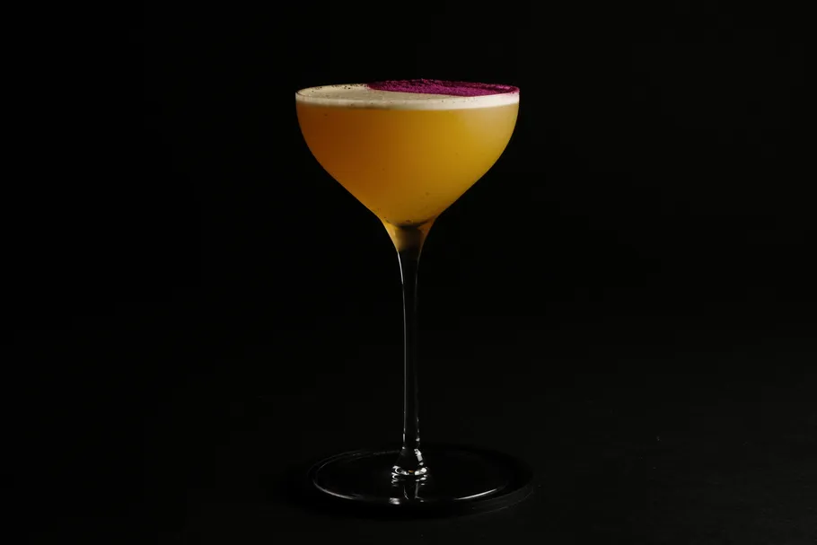 Yellow cocktail in glass on black background.