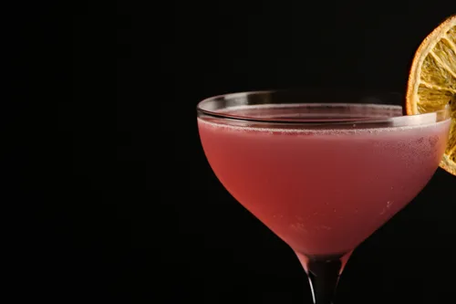 Rosa Cocktail mit getrockneter Zitrusgarnitur.