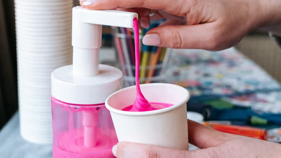 Hand dispensing pink liquid into a cup.