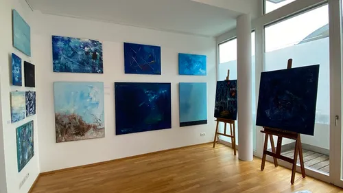 Galerie mit abstrakten blauen Gemälden an Wänden.