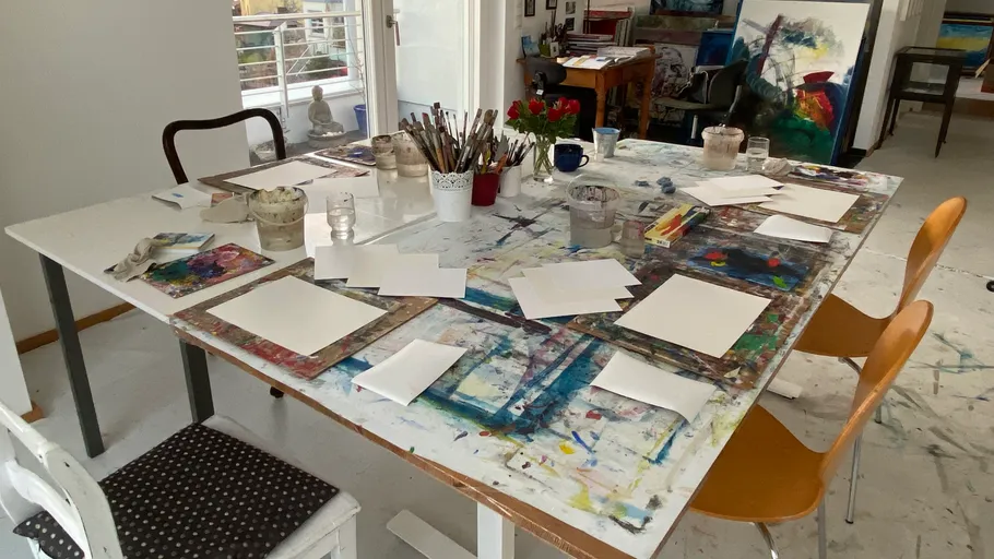 Kunststudio mit Papieren und Pinseln auf Tisch.