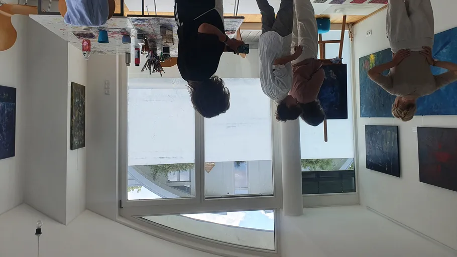 Personen im Atelier besprechen Gemälde.