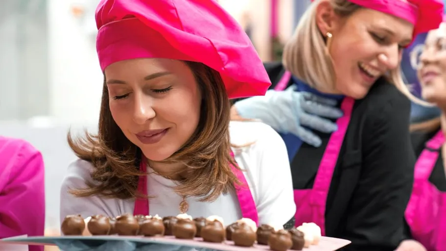 Frauen in pinken Hüten genießen Pralinenkurs.