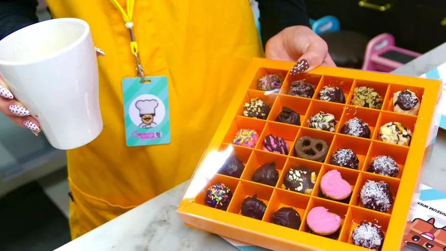Person holding chocolates and a white cup.