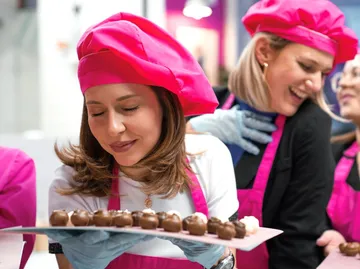 Frauen in pinken Mützen halten Schokoladentablett.