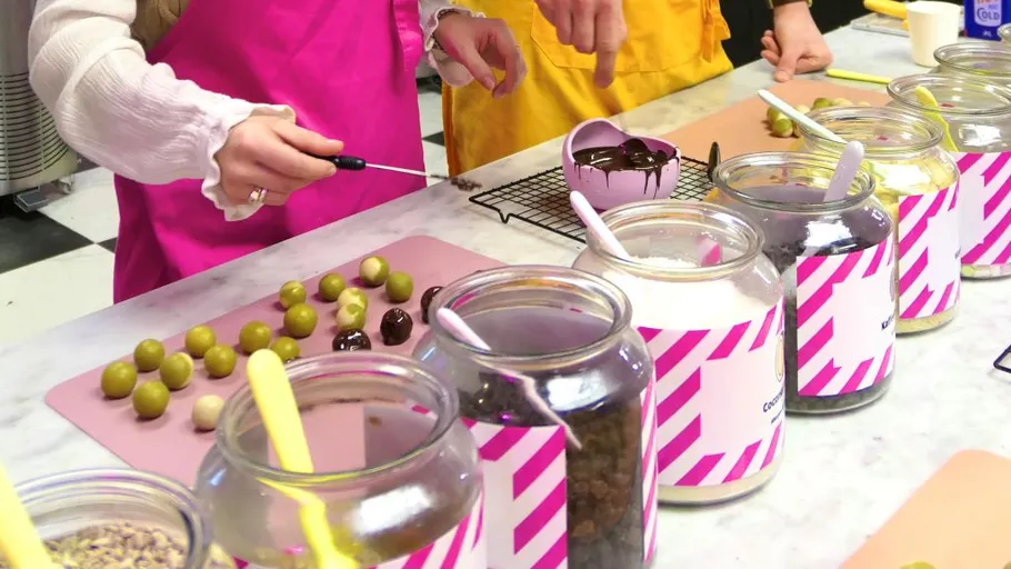 People decorating sweets on a kitchen counter.
