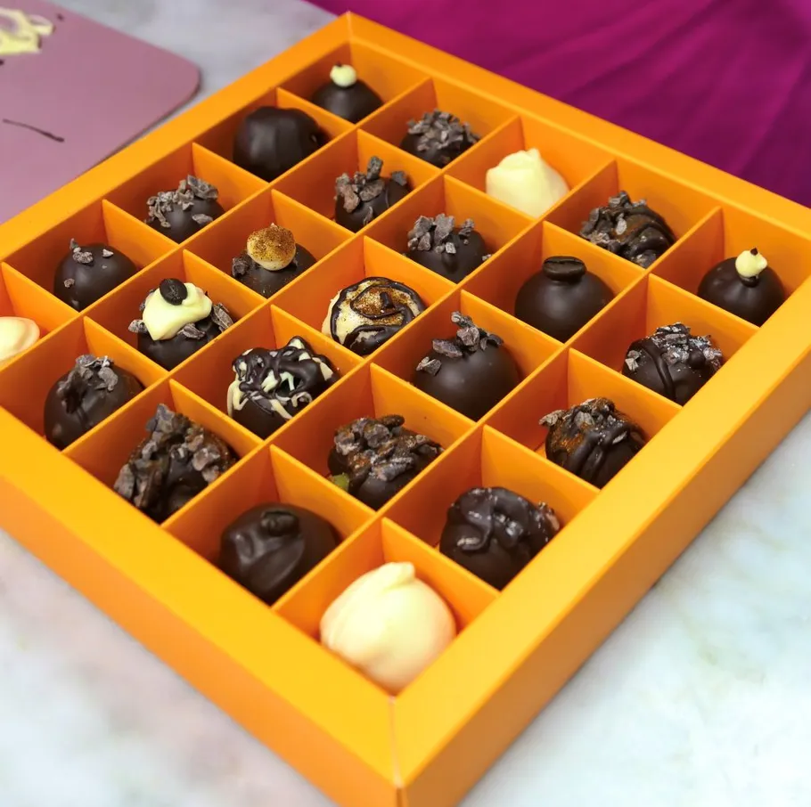 Chocolate truffles arranged in an orange box.