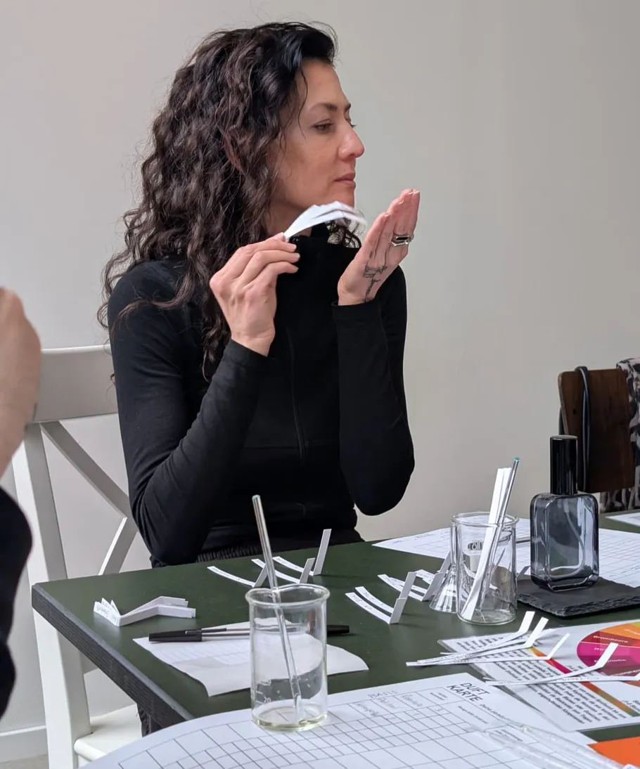 Frau riecht an Papierstreifen am Tisch.