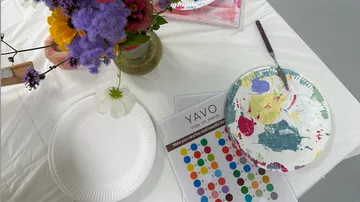 Paint supplies on table with flowers.