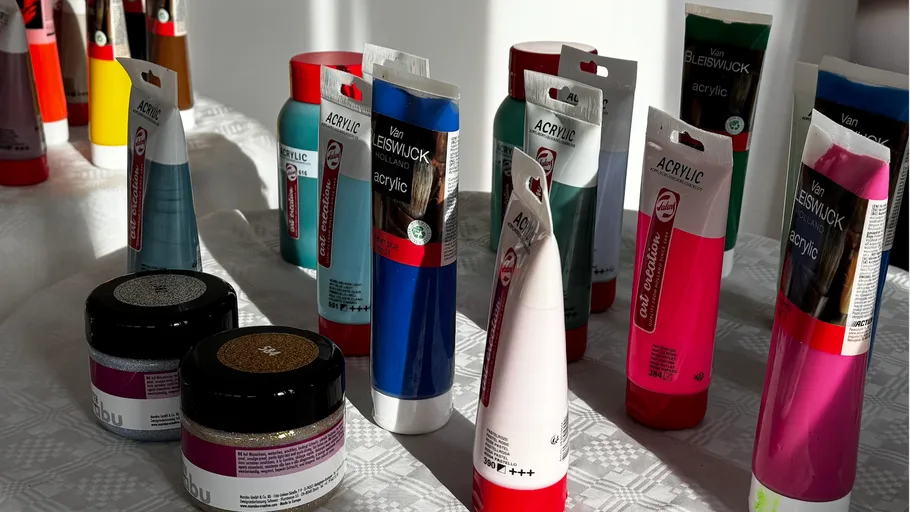 Acrylic paints and glitter jars on a table.