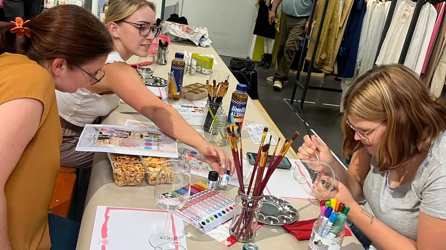 Three women painting at a table indoors.