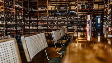 Bar mit Stühlen und Regalen mit Flaschen.