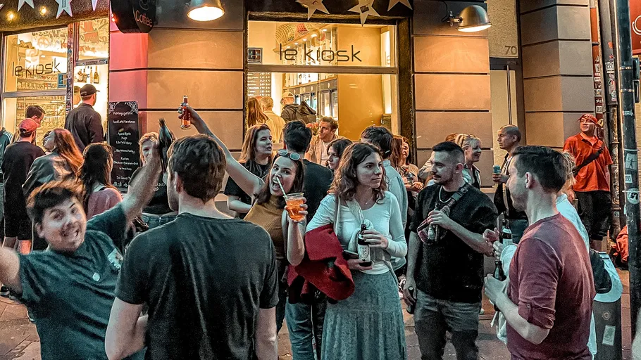 Group of people socializing outside a bar at night.