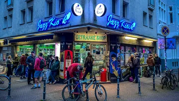People gather outside Jazz Kiosk in city street.