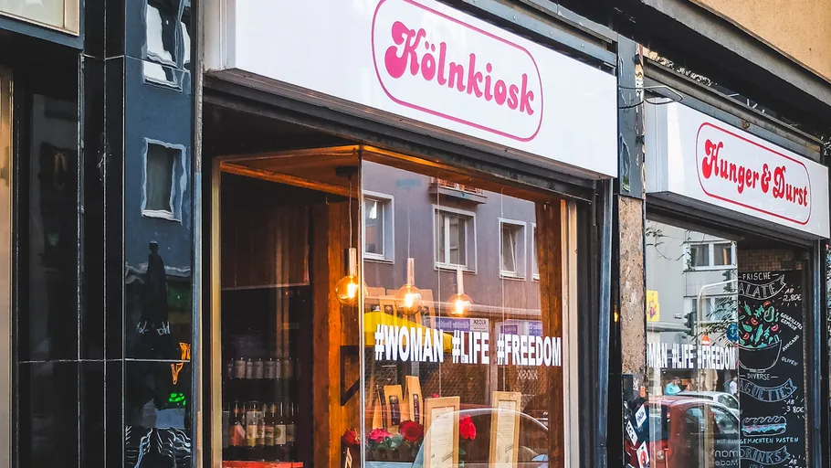 Storefront with signs Cologne Kiosk and hashtags.