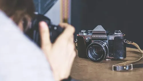 Alte Kamera wird von Person auf Tisch fotografiert.