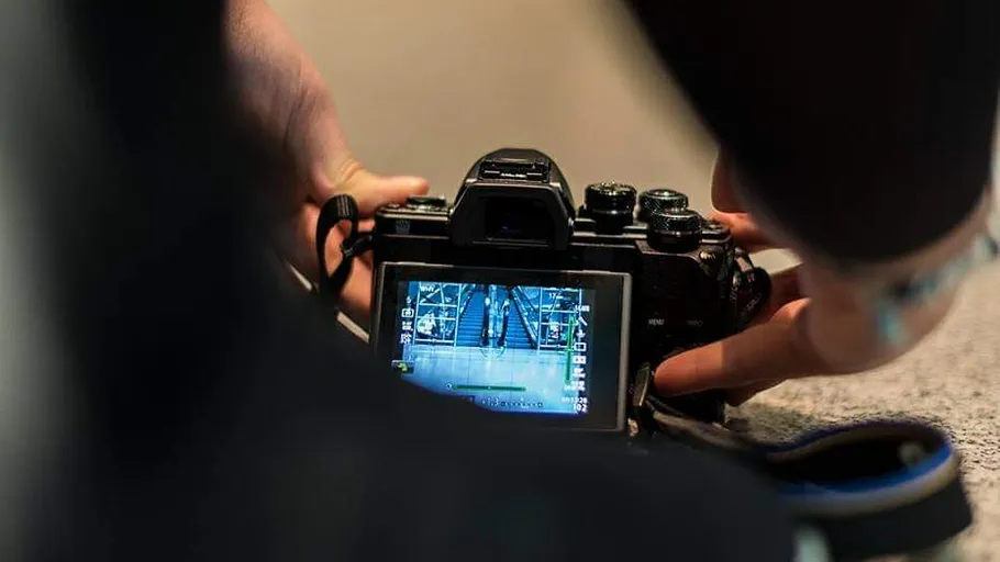 Person adjusting camera, viewing image on screen.