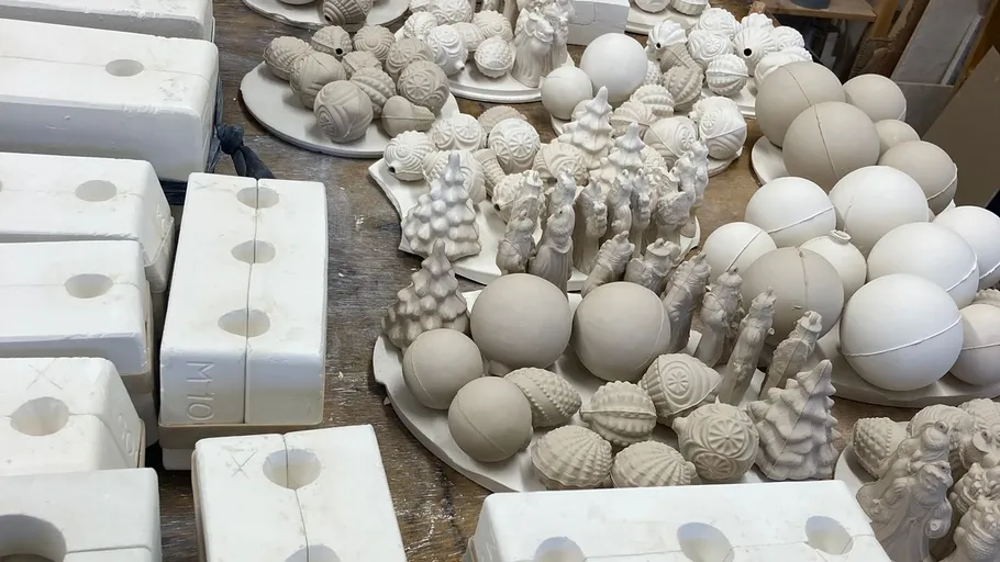 Unpainted ceramic ornaments on a workshop table.