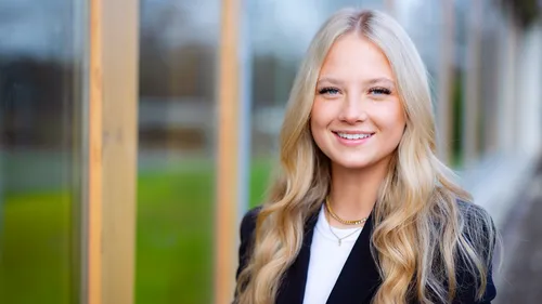 Woman smiling outside near a building.