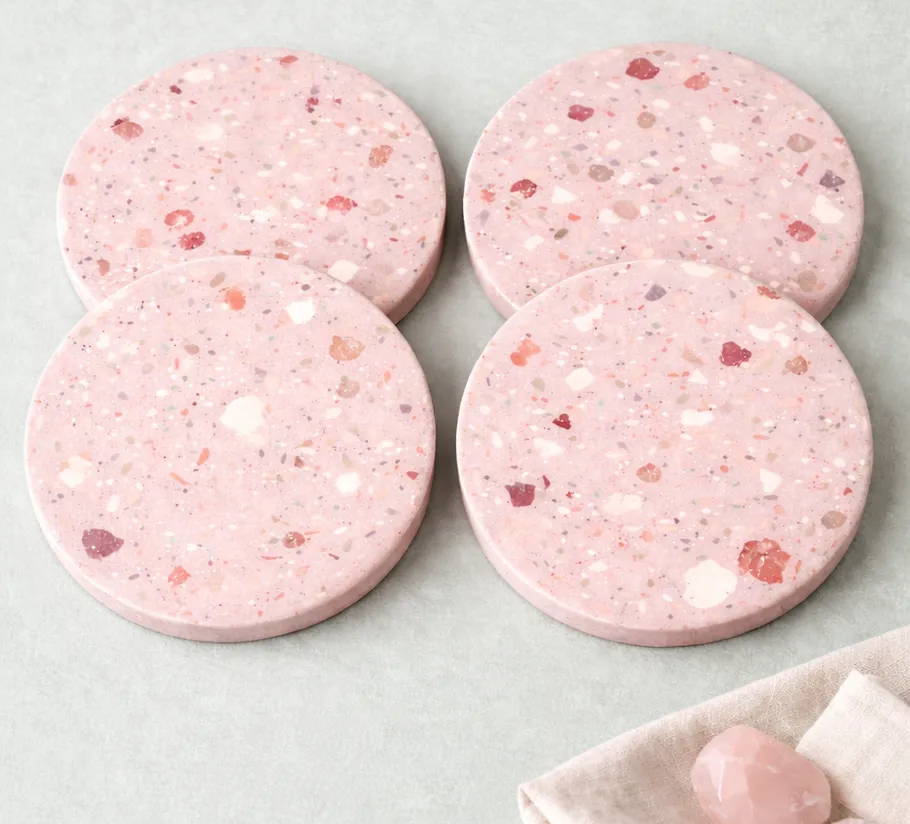 Vier rosa Terrazzo-Untersetzer auf einem Tisch.