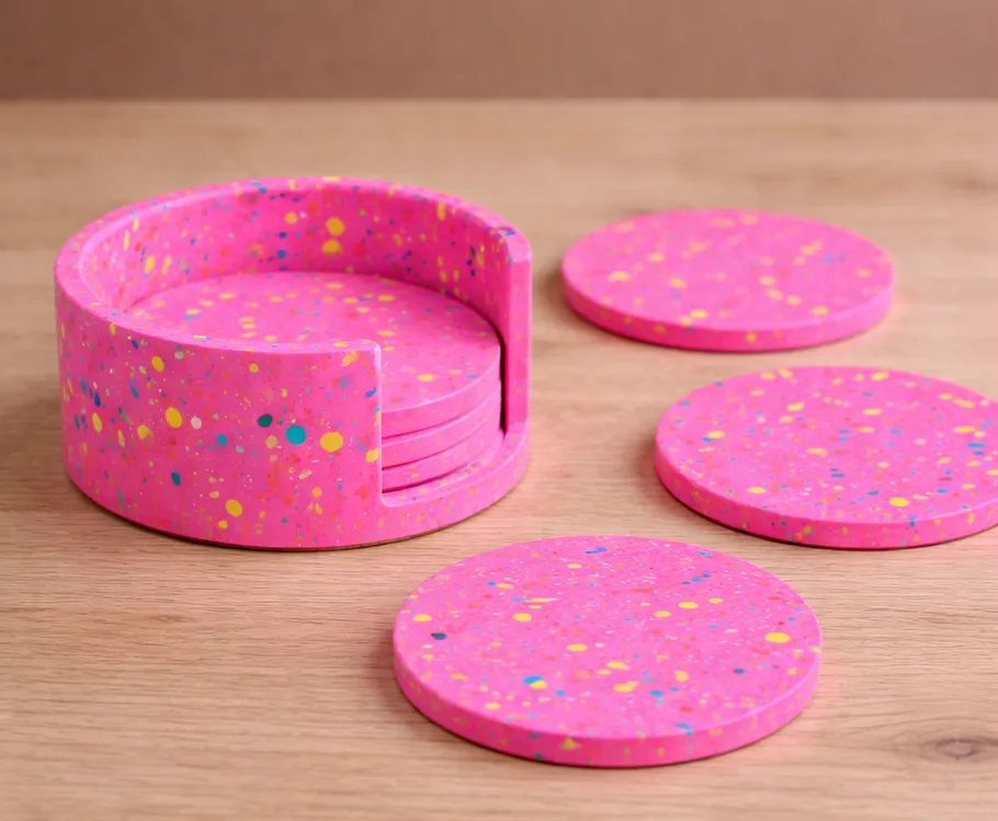Pink speckled coasters on wooden table.