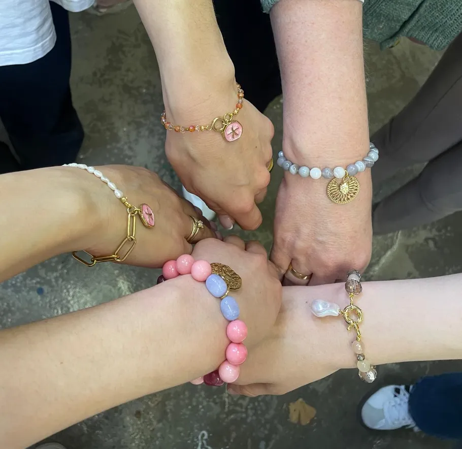 Hände mit bunten Armbändern im Kreis.