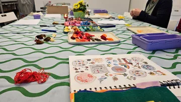 Craft table with embroidery materials and patterns.