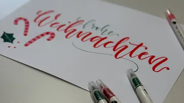 Handgeschriebene 'Frohe Weihnachten'-Karte mit Stiften.