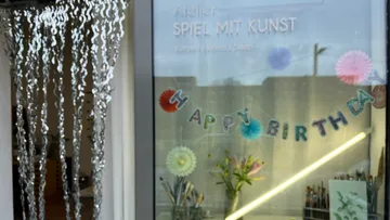 Art studio window with birthday decorations.