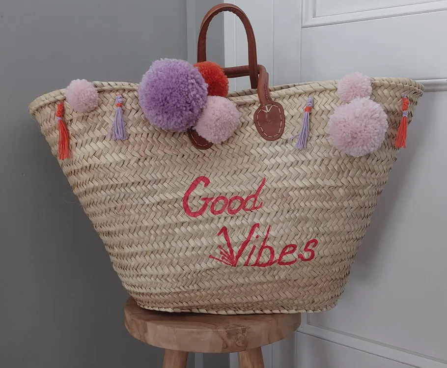 Strohkorb mit Pom-Poms und 'Good Vibes' Text.