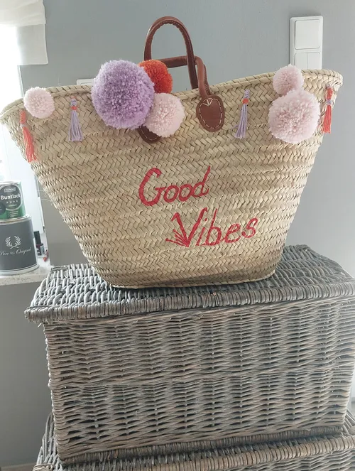 Geflochtener Korb mit Pompons auf Korbtruhe.