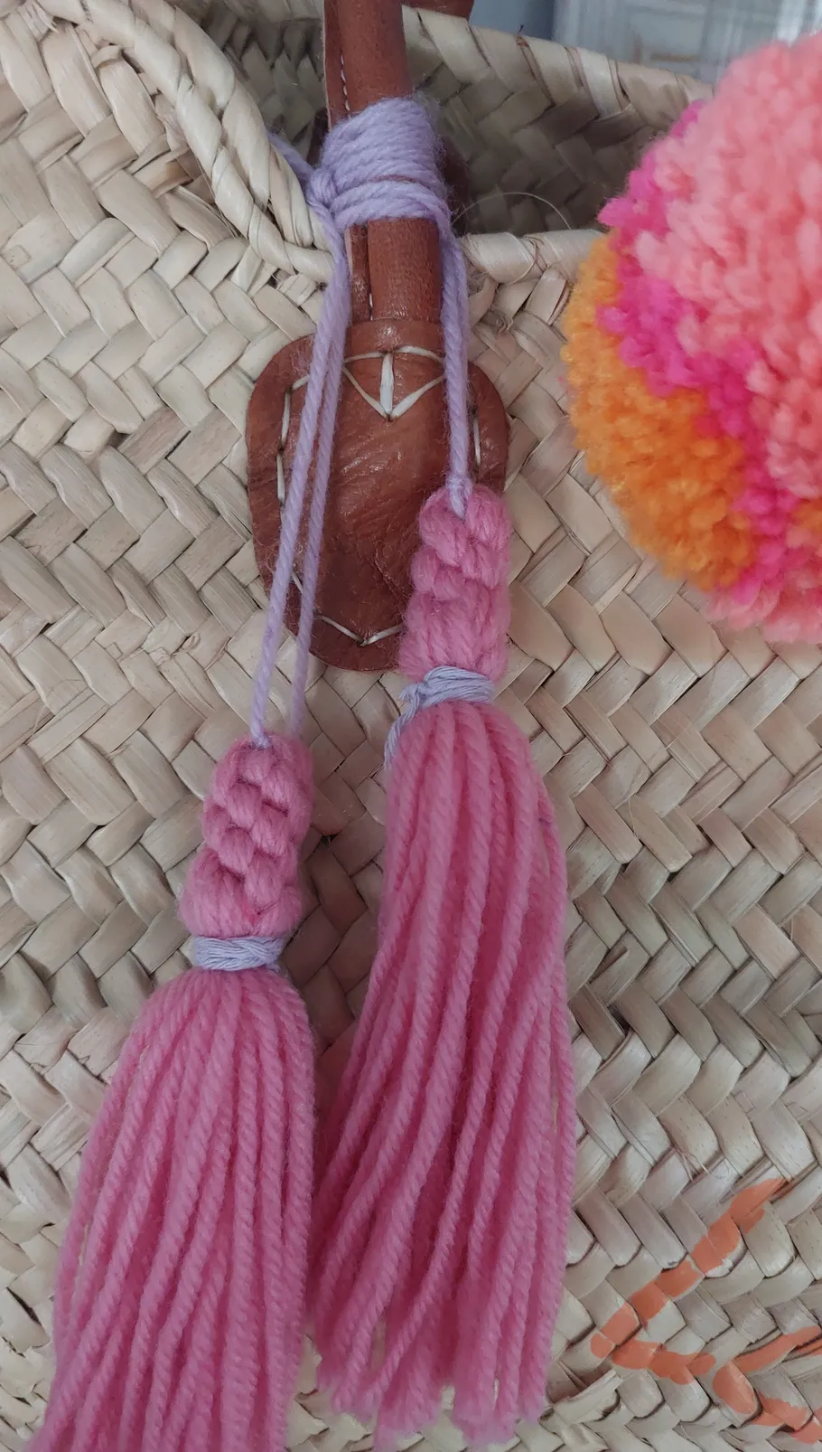 Pink tassels hanging from woven basket.