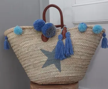 Geflochtene Tasche mit blauen Quasten auf Hocker.
