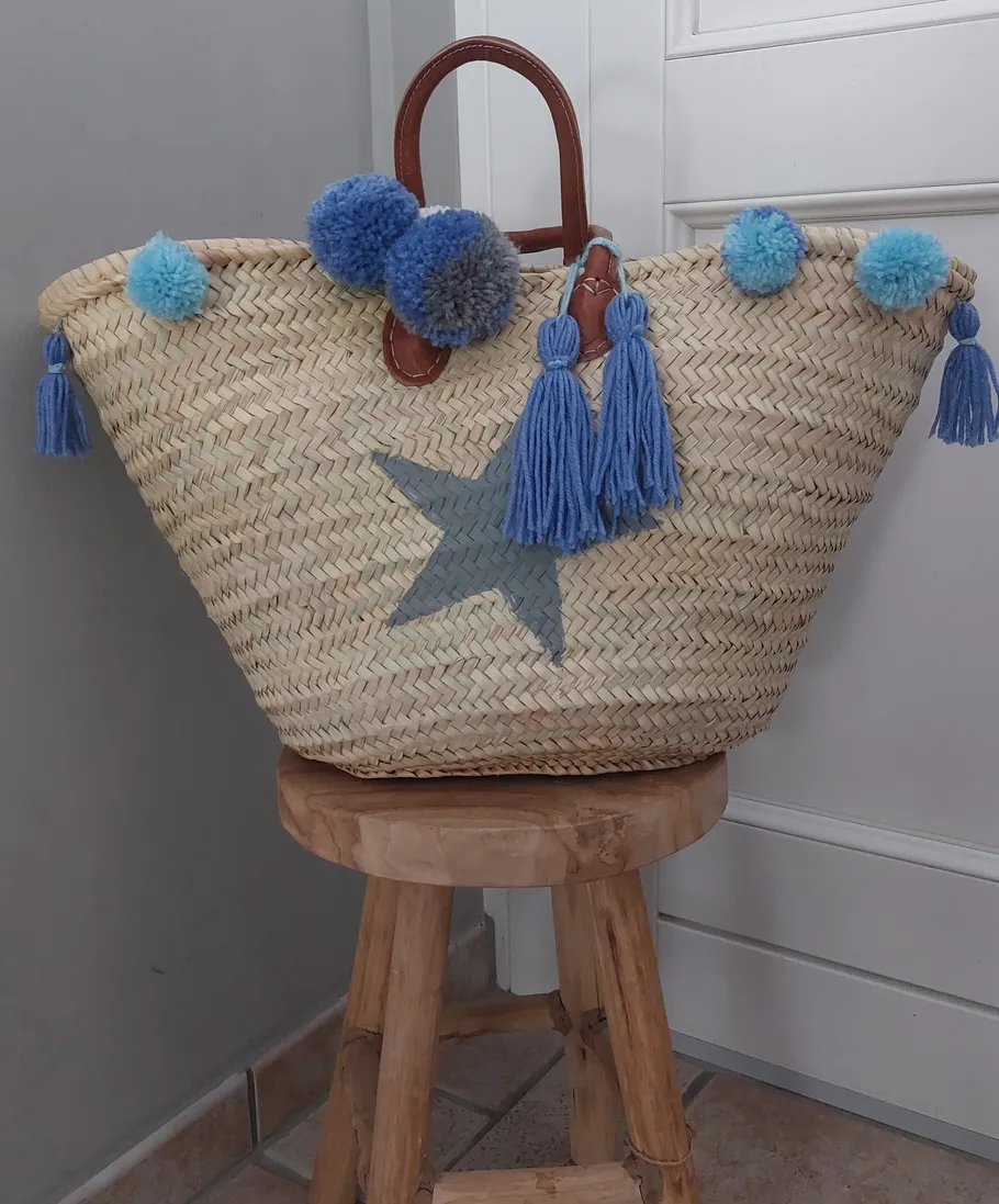 Woven bag with blue tassels on stool.
