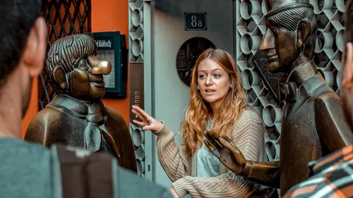Woman explaining statues to an audience outside.