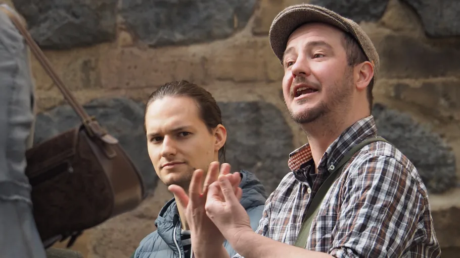 Two men outdoors in conversation, one gesturing.