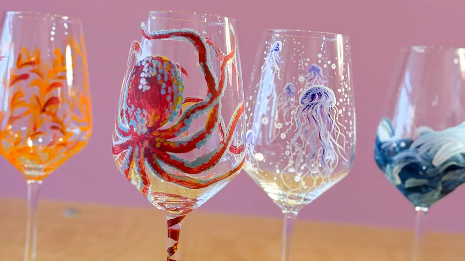 Colorful painted wine glasses on wooden table.