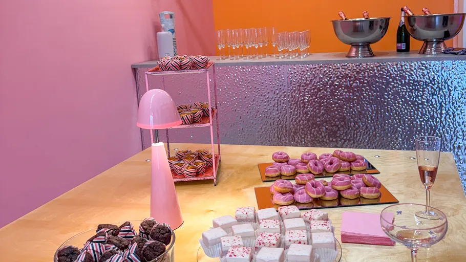 Dessert table with pink-themed treats and beverages.