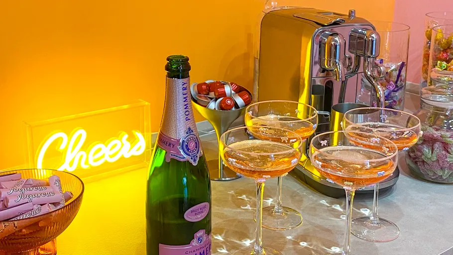 Champagne bottle with glasses on countertop.