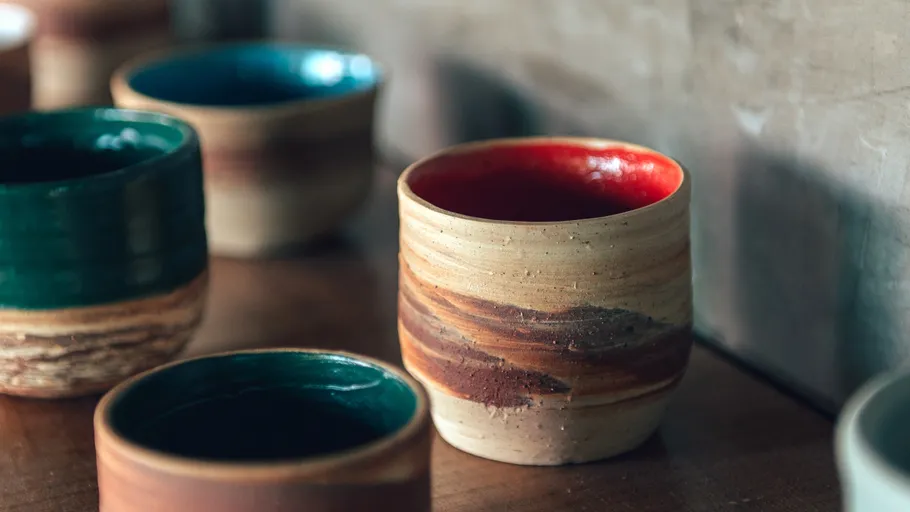 Ceramic cups on wooden surface, earthy colors.