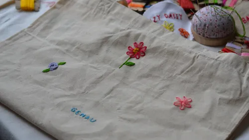 Bestickte Tasche mit Blumen und 'genau'-Text.