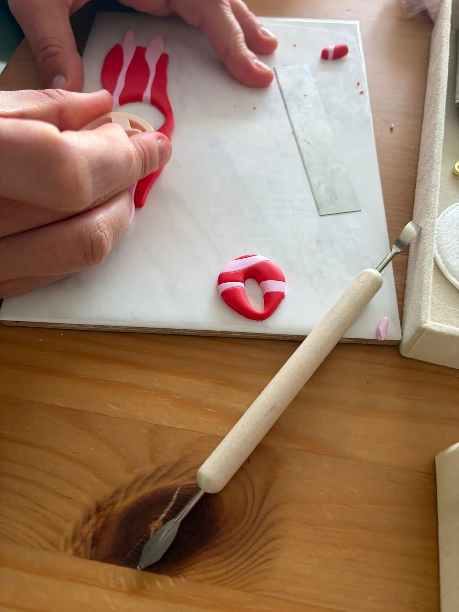 Hände formen Ton auf einem Holztisch.