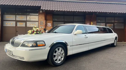 Weiße Limousine mit Blumendekoration vor Garage.