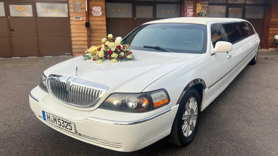 Weiße Limousine mit Blumenarrangement draußen geparkt.