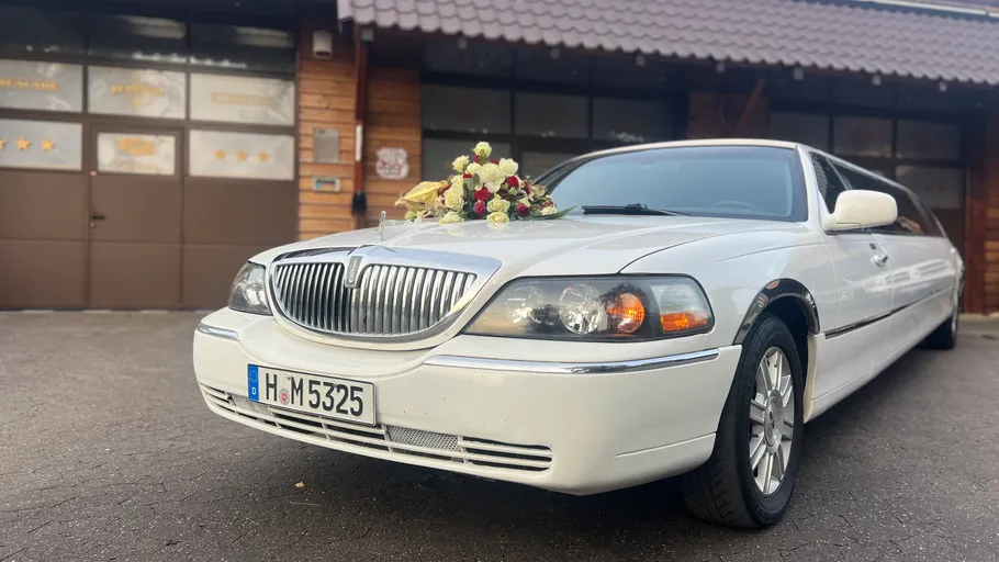Weiße Limousine mit Blumendekoration, draußen geparkt.