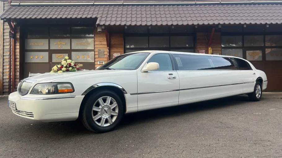 White limousine parked outside wooden building.