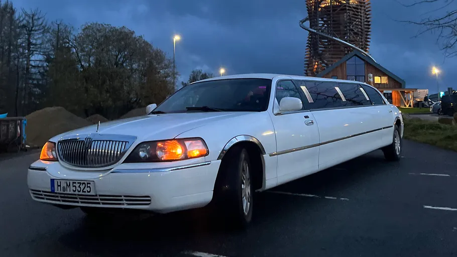 White limousine parked on dark street.