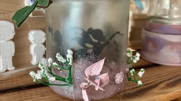 Decorative jar with flowers and silhouette inside.