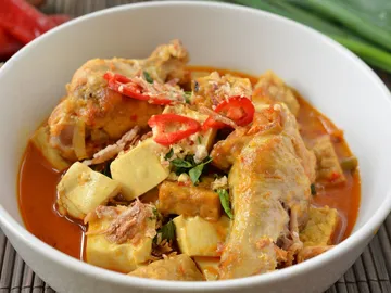 Hühnchen und Tofu in würziger Sauce in einer Schüssel.