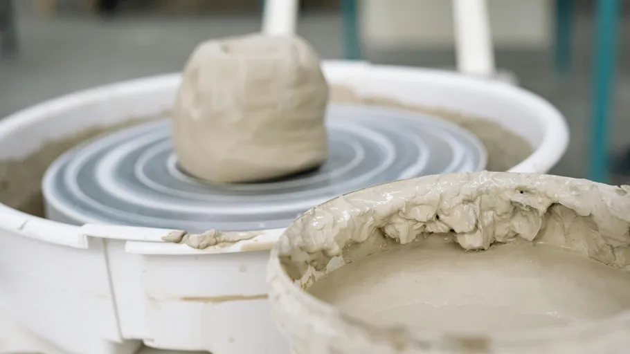 Clay ball on pottery wheel in workshop.